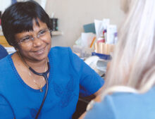 A health professional wearing a stethoscope in consultation with a patient
