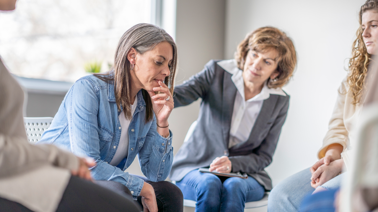 Two people sat together, one person looking concerned at the other.