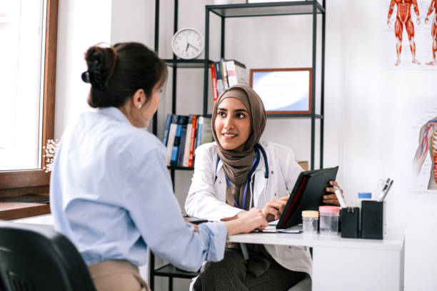 Close up of a young Caucasian woman having an Asian doctor's appointment at medical clinic.