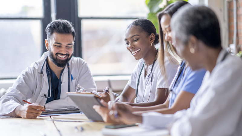 A group of health professionals sat around a table chatting and laughing